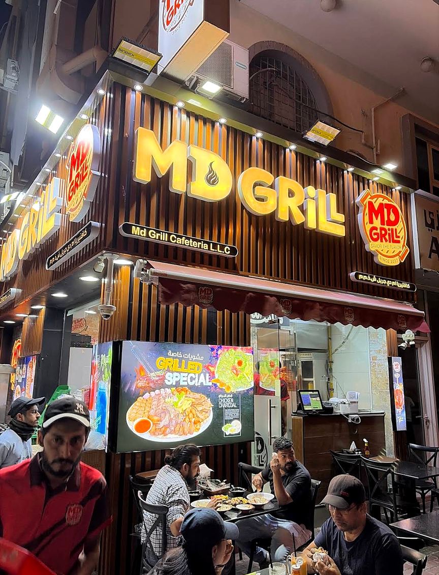 The lit MD GRILL storefront at night in Al Ras, Dubai